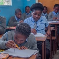 A learner writing carefully in her notebook